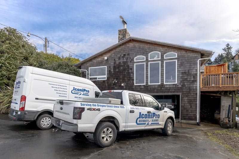 Two IconiPro service trucks parked in front of a customer residential home